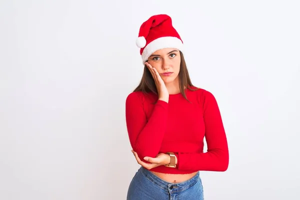 年轻美丽的女孩戴着圣诞圣诞圣诞礼帽 站在孤独的白色背景上 满脑子疲惫而厌烦 双手交叉地陷入忧郁症 — 图库照片