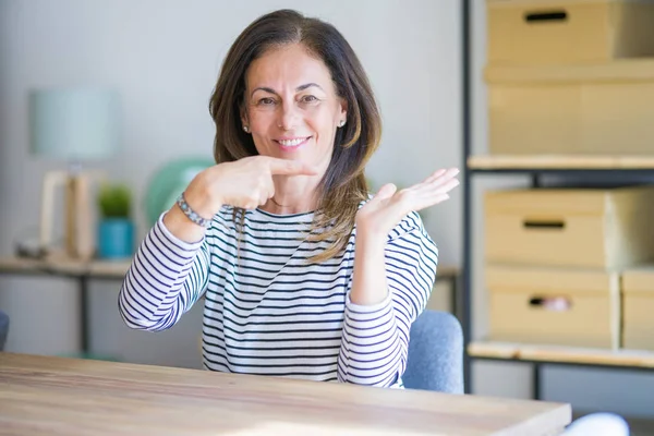 Mujer Mayor Mediana Edad Sentada Mesa Casa Sorprendida Sonriendo Cámara —  Fotos de Stock