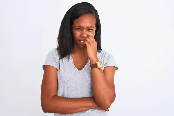 孤立した背景にカジュアルなTシャツを着た美しい若いアフリカ系アメリカ人女性は 口の上で爪をかむ手でストレスと緊張を見ています 不安の問題 — ストック写真