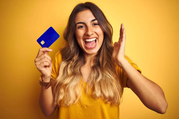 Młoda Piękna Kobieta Trzyma Kartę Kredytową Żółtym Tle Bardzo Szczęśliwy — Zdjęcie stockowe