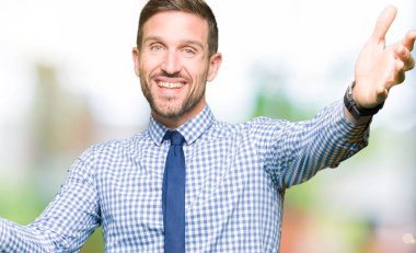 Yakışıklı iş adamı sarılmak için açık kollar ile gülümseyen kamera bakarak kravat giyiyor. Mutluluğu kucaklayan neşeli ifade.