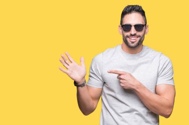 Yakışıklı delikanlı izole arka el ve parmak ile işaret çok mutlu üzerinde güneş gözlüğü takıyor