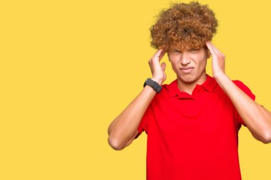 Afro saçlı genç yakışıklı adam stres nedeniyle baş ağrısı için el ile kırmızı t-shirt giyiyor. Acı çeken migren.