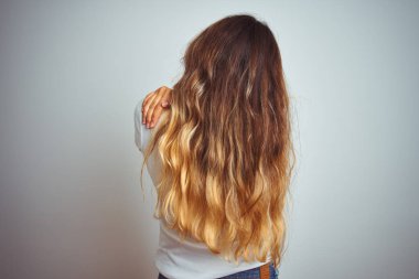 İzole edilmiş arka plan üzerine günlük beyaz tişört giyen genç güzel bir kadın kendine mutlu ve pozitif bir şekilde sarılıyor. Sevgi ve özgüven.