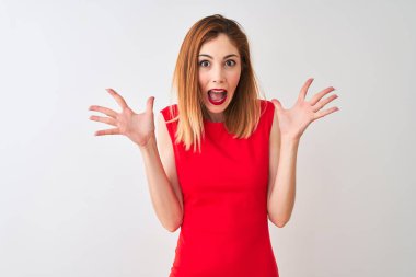 Kızıl saçlı iş kadını zarif kırmızı elbiseler giyip izole edilmiş beyaz arka planda durmuş çılgın ve başarıyı kollarını kaldırıp heyecanla haykırarak kutluyor. Kazanan konsept