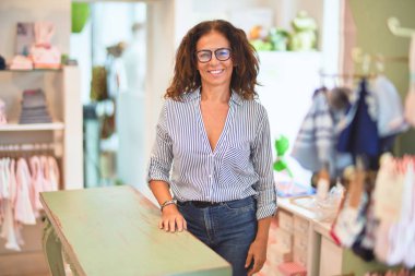 Orta yaşlı, güzel elbise dükkanı sahibi, gülümseyen mutlu ve kendinden emin müşteriler tezgahta bekliyor.