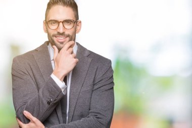 Genç yakışıklı iş adamı emin çapraz kollar ve çeneme kaldırdı el ile gülümseme ile kameraya bakarak izole arka plan üzerinde. Pozitif düşünce.