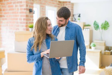 Genç çift araba etrafında bir odada duran bilgisayar dizüstü bilgisayar kullanarak