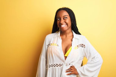 Güzel Afro-Amerikalı kız bikini ve yaz elbisesi giyip gülümsüyor.