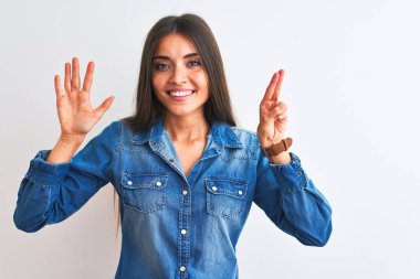 Genç güzel kadın rahat kot gömlek giyerek izole beyaz arka plan üzerinde duran gösteren ve emin ve mutlu gülümserken parmakları ile yedi numara işaret.