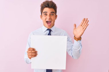 Genç yakışıklı iş adamı pembe arka planda duruyor. Çok mutlu ve heyecanlı. Kazanan ifade zaferi büyük bir gülümsemeyle kutluyor.