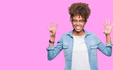 Güzel genç Afro-Amerikan kadın gözlük gösterilen ve parmakları ile işaret izole arka plan üzerinde dokuz kendinden emin ve mutlu gülümseyerek iken numara.