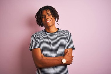 Sarı çizgili tişört giyen Afro bir adam izole edilmiş pembe arka planda duruyor ve kollarını kavuşturup kameraya bakıyor. Pozitif kişi.