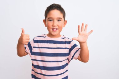 Güzel çocuk, sıradan çizgili tişört giyiyor. İzole edilmiş beyaz arka plan üzerinde duruyor. Altıncı parmaklarıyla işaret ediyor..