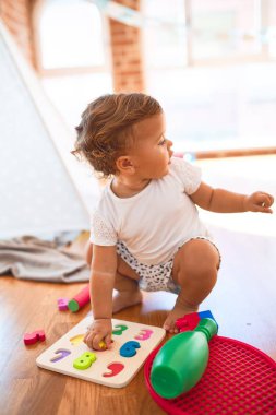 Anaokulundaki bir sürü oyuncağın etrafında matematik bilmeceleri kullanarak sayıları öğrenen sevimli çocuk.