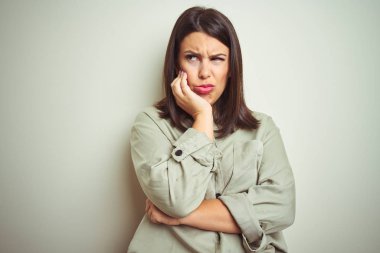 Genç güzel esmer kadın izole arka plan üzerinde yeşil gömlek giyen yorgun görünümlü ve çapraz kolları ile depresyon sorunları ile sıkılmış düşünme.