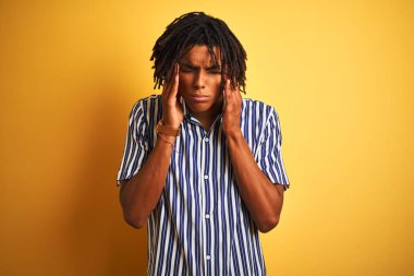 Rastgele çizgili tişört giyen Afro bir adam izole edilmiş sarı arka plan üzerinde, baş üstünde baş ağrısı var çünkü stres. Migren ağrısı..