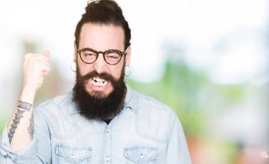 Uzun saç ve sakal kızgın ve kızgın gözlüklü genç hipster adamla yumruk hayal kırıklığı ve öfke ile bağırarak süre öfkeli yükselterek. Öfke ve agresif kavramı.