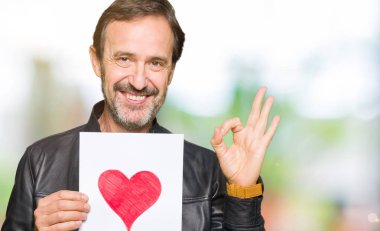 Parmak ile ok işareti yapıyor kırmızı kalp ile kağıt tutan yakışıklı Orta Çağ adam, mükemmel sembolü