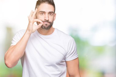 Açık havada beyaz tişört giyen yakışıklı bir adam arka plan ağzı ve dudakları parmaklarıyla fermuar gibi kapalı. Gizli ve sessiz, tabu konuşması
