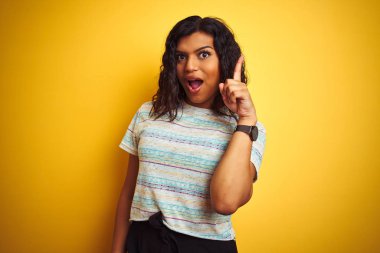 Güzel transseksüel kadın izole edilmiş sarı arka plan üzerine tişört giyip başarılı bir fikir işaret ediyor. Heyecanlı ve mutlu. Bir numara..