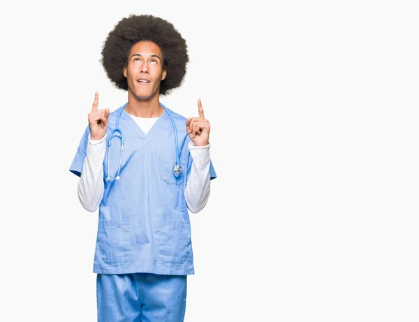 アフロ髪の若いアフリカ系アメリカ人医師男びっくり驚いて見上げると指で指していると腕を上げた — ストック写真