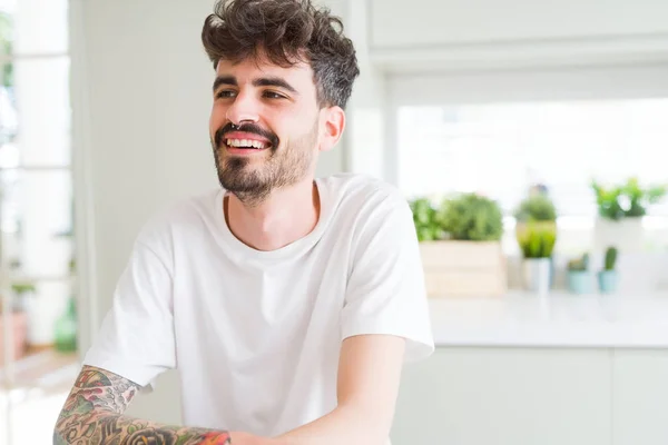 Joven guapo sonriendo alegre a la cámara con cruzado un — Foto de Stock