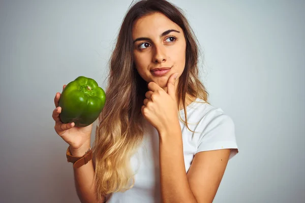 Mladá Krásná Žena Drží Zelený Pepř Nad Bílým Izolovaným Pozadím — Stock fotografie