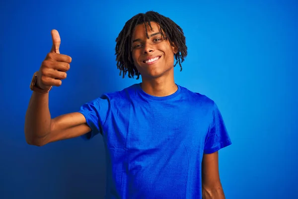 穿着T恤衫站在孤立的蓝色背景上 手拿着快乐的大拇指做手势的非裔美国人 在镜头前看着成功的表情 — 图库照片