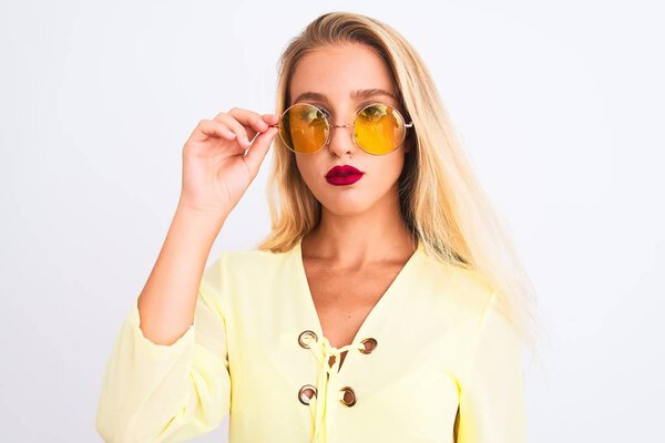 Young beautiful woman wearing yellow t-shirt and sunglasses over isolated white background with a confident expression on smart face thinking serious