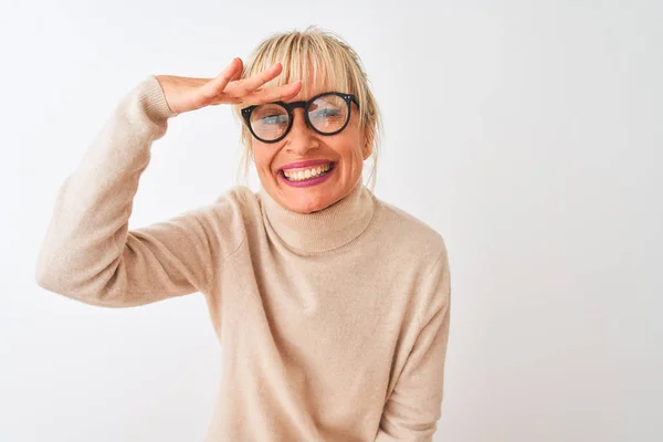 孤立した白い背景にタートルネックのセーターと眼鏡を身に着けている中年の女性は非常に満足し 遠くを見て笑顔頭の上に手で 検索の概念 — ストック写真