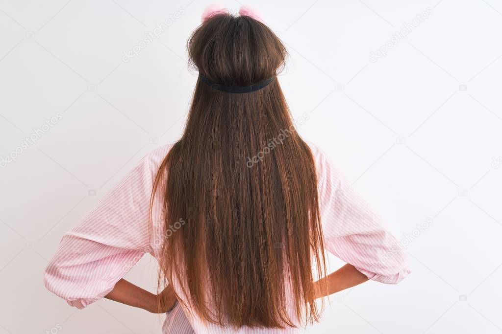 Young beautiful woman wearing sleep mask and pajama over isolated white background standing backwards looking away with arms on body