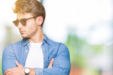 İkna ve kendine güvenen genç yakışıklı adam tarafına silahlarla seyir gülümseyen izole arka plan üzerinde güneş gözlüğü takıyor geçti