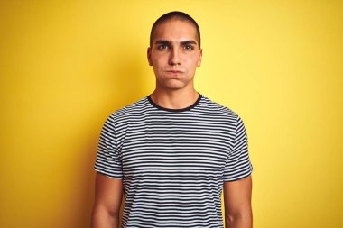 Sarı izole edilmiş arka plan yanakları üzerine çizgili tişört giyen yakışıklı genç adam komik suratlı. Havayla şişmiş ağız, çılgın bir ifade..