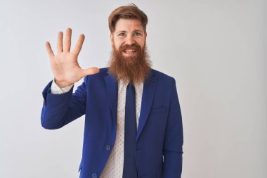 İzole edilmiş beyaz arka plan üzerinde duran genç kızıl saçlı iş adamı beş numaralı parmaklarıyla gülümseyerek kendinden emin ve mutlu bir şekilde duruyor..