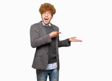 Genç yakışıklı iş adamı ile hayrete ve el ile sunulması ve parmak ile işaret ederken kameraya gülümseyen gözlüklü afro.