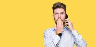 Akıllı telefon kapağı ağız üzerinde konuşan genç yakışıklı adam iş hata için utanç ile şok, korku ifadesi, sessizlik, gizli kavram korkmuş