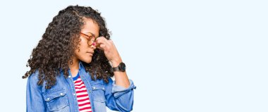 Kıvırcık saçlı Genç güzel kadın gözlük yorgun sürtünme burun ve gözleri yorgunluk ve baş ağrısı hissi giyiyor. Stres ve hayal kırıklığı kavramı.