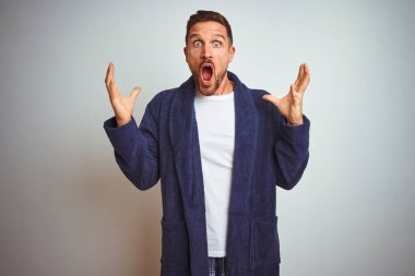 Genç adam rahat pijama ve cüppe giyen sabah izole arka plan üzerinde deli kutluyor ve kollarını kaldırdı ve açık gözleri heyecan çığlık ile başarı için hayran. Kazanan kavramı