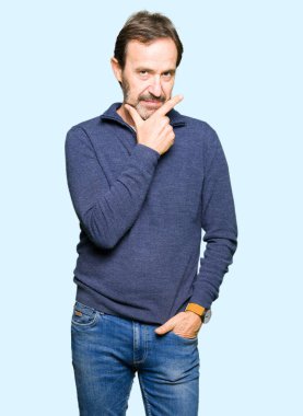 Orta yaş yakışıklı adam emin çapraz kollar ve çeneme kaldırdı el ile gülümseme ile kameraya bakarak bir kazak giyiyor. Pozitif düşünce.