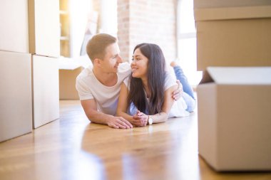 Genç güzel çift karton kutular etrafında yeni evde yatarken