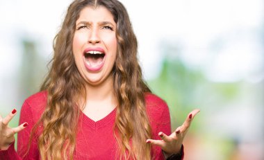 Kırmızı kazaklı çılgın ve kızgın bağırarak ve agresif ifade ve silah kaldırdı bağırmaya giyen genç güzel kadın. Hayal kırıklığı kavramı.