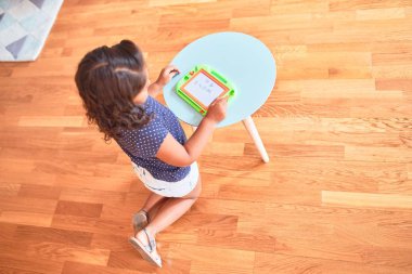 Anaokulunda dijital tahta kullanarak güzel bir kız şirin bir resim çiziyor.