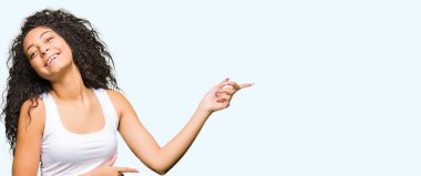 Gülümseyen ve iki ile işaret kamera bakarak kıvırcık saçlı Genç güzel kız eller ve yan parmak.