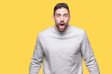 Şüpheci ve alaycı, şok karşısında izole arka plan üzerinde sweatshirt giyen genç yakışıklı adam açık ağız ile şaşırttı