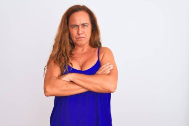 Orta yaşlı olgun bir kadın beyaz soyutlanmış arka planda duruyor şüpheci ve gergin, yüzünde çapraz kollu tasvip etmeyen bir ifade. Negatif kişi.