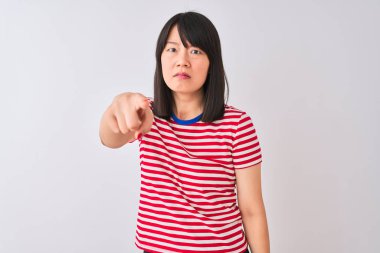 İzole edilmiş beyaz arka plan üzerine kırmızı çizgili tişört giyen genç ve güzel Çinli kadın kameraya kızgın ve sinirli bir şekilde bakıyor.