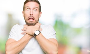 Rahat beyaz tişört giyen yakışıklı adam çığlık atıyor ve çünkü ağrılı boğmak. Sağlık problemi. Asphyxiate ve intihar konsepti.