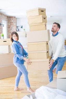 Genç güzel çift yeni evde karton kutu yığını tutan