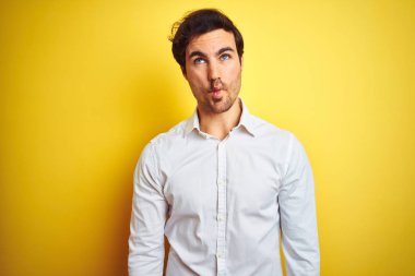 Zarif tişört giyen yakışıklı genç işadamı izole edilmiş sarı arka planda duruyor dudaklı balık suratı yapıyor, çılgınca ve komik hareketler yapıyor. Komik ifade.